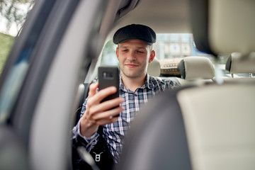 Photo of man with phone in his hands driving car.