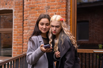 two girls are watching photos on a smartphone