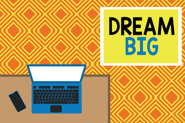 Conceptual hand writing showing Dream Big. Concept meaning To think of something high value that you want to achieve Office working place laptop lying wooden desk smartphone