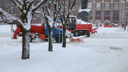 Tractor cleaning the road from the snow. Excavator cleans the streets of large amounts of snow in city. Removing snow with plow.