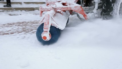 Snowplow removing fresh snow from city square. Tractor with snowplow equipment removing snow from streets in snow blizzard.