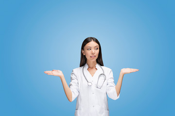 A young Asian woman doctor is scaling with her arms two different options in front of isolated and...