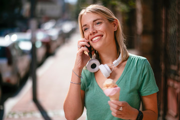 Beautiful girl talking on phone holding ice cream