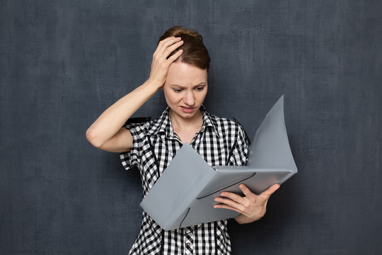 Portrait of bewildered woman looking at documents in folder
