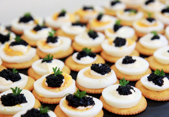 Crackers are topped with boiled eggs, black caviar and parsley. It is a simple and delicious snack.