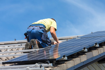 Installing solar photovoltaic panel system. Solar panel technician installing solar panels on roof....