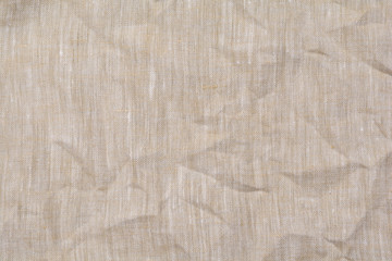 Crumpled beige linen fabric background, close up