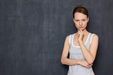 Portrait of focused serious woman touching chin with hand