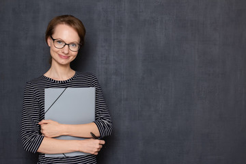 Portrait of happy friendly girl holding folder and pen in hands