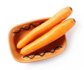 Carrots in clay bowl isolated on white background, top view