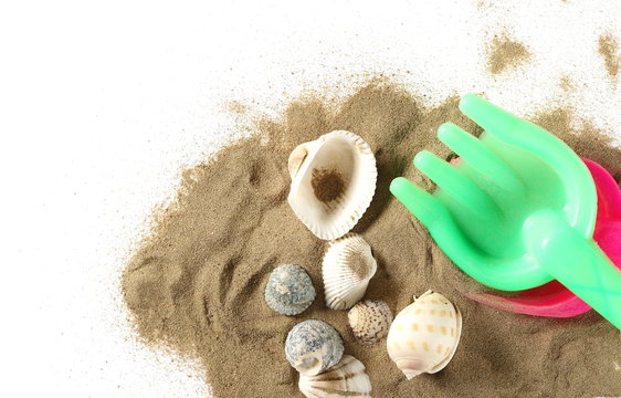 Beach toys for kids, plastic tools in sand pile with seashells isolated on white background, top view