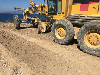 Fototapeta na wymiar Planning of a road surface. Motor grader during road construction works. Earthmoving, excavations, digging