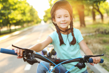Fototapeta na wymiar Cute girl riding bicycle outdoors
