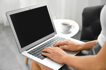 Young woman with laptop sitting on sofa, closeup