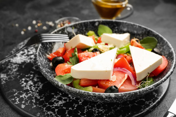 Plate with tasty Greek salad on table