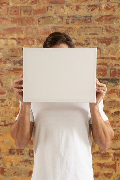 Blank canvas held in front of brick wall