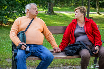Elderly couple resting sitting on a bench in the Park