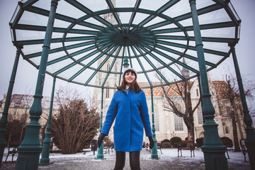 A tourist woman in trendy blue coat near historical architecture of a catholic gothic Matthias...
