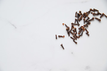 Dried cloves on grey marble background with copy space. Spice for hot tea, winter drinks and food. Close up and top view