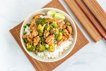 Broccoli and Chicken Stir-Fried in a Bowl with Lemon and Chopsticks Directly Above Photo.