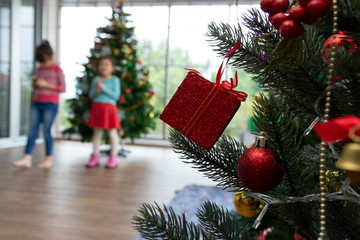 Christmas tree with blur little girls dancing and funny before select variety of gifts at this Christmas party tonight. She looks happy and has a bright smile. Holiday concept.