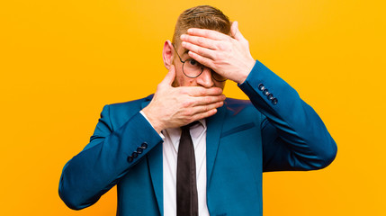 young red head businessman covering face with both hands saying no to the camera! refusing pictures...