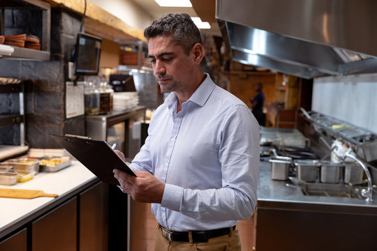 Restaurant manager holding a clipboard in a kitchen