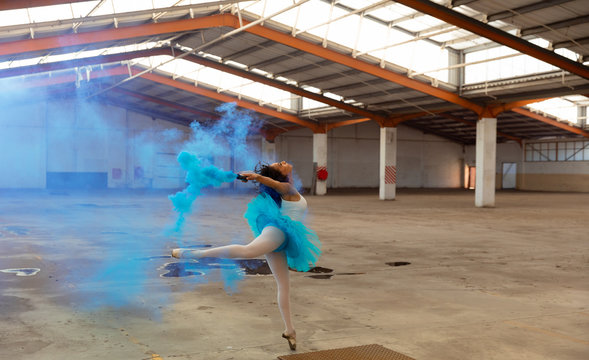 Female dancer in an empty warehouse holding smoke grenade