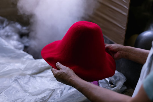 Man holding a hat in a hat factory workshop - Powered by Adobe