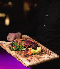 Fried meat with vegetables on wooden board