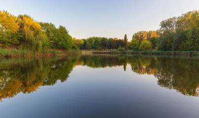 Resting people on the shore of a beautiful pond.