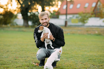 Young man plays with Jack Russell puppies.