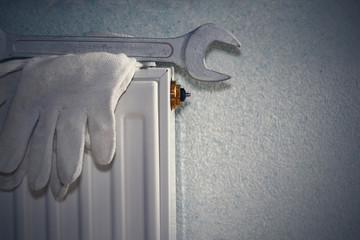 Man is repairing radiator battery in the room. Maintenance repair works renovation in the flat. Heating restoration. Wrench in hands