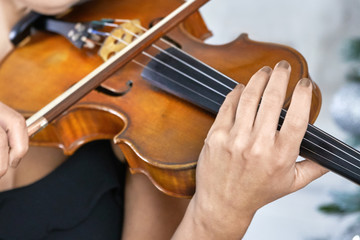 Female violinist with manicure on nails plays violin close up