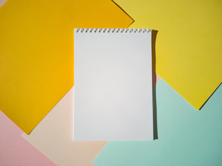 Blank notepad on a spiral with white pages on colored sheets of paper. Top view, minimalism, flat lay. Place for text, copy space.