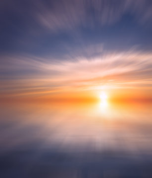 Bright sunset with rays on the background of soft clouds over the sea. © Sviatoslav Khomiakov