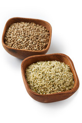 Organic whole and shelled hemp seeds in wooden bowl  isolated on white background
