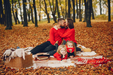 Fototapeta premium Family in a autumn park. Woman in a red sweater. Cute childrens with parents