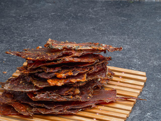 Dried meat slices in wooden board