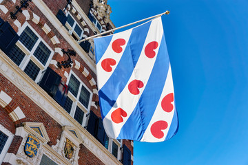 Frisian flag on the old renaissance style town hall in Franeker Friesland The Netherlands under a blue sky with copy space.      
