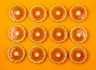 Sweet cookies with orange jelly. Amber sweet cookie with jelly flavored orange on orange background. Creative minimal background. Food concept.