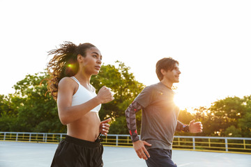 Photo of multinational focused couple running together