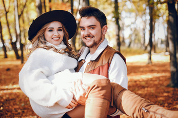 Couple have fun in a autumn park. Cute blode in a white sweater.