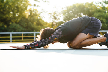 Photo of concentrated brunette man doing exercises on mat
