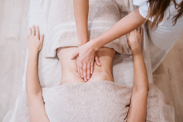 young caucasian physiotherapist Woman giving a stomach massage to female patient in clinic. Physiotherapy and body care concept. top view - Powered by Adobe
