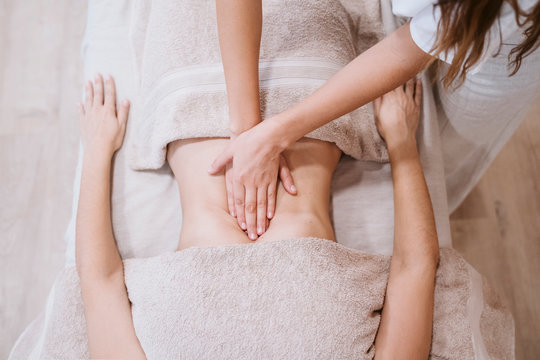 young caucasian physiotherapist Woman giving a stomach massage to female patient in clinic. Physiotherapy and body care concept. top view