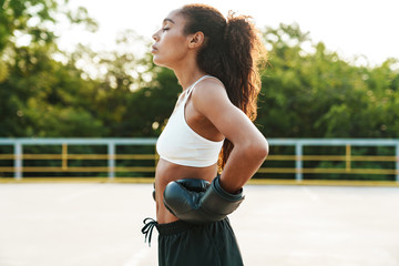 Photo of calm woman in boxing gloves standing while doing workout