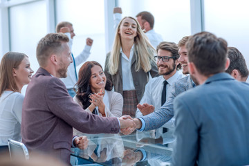 Fototapeta premium smiling business partners shaking hands, to the applause of the business team