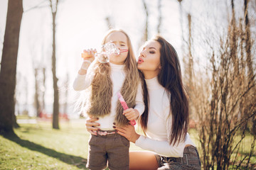 Fashionable mother with daughter. Family in a spring park. Mother's day