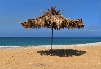 Fototapeta na wymiar natural dryed palms unbrella in front of the sea in mediterranee